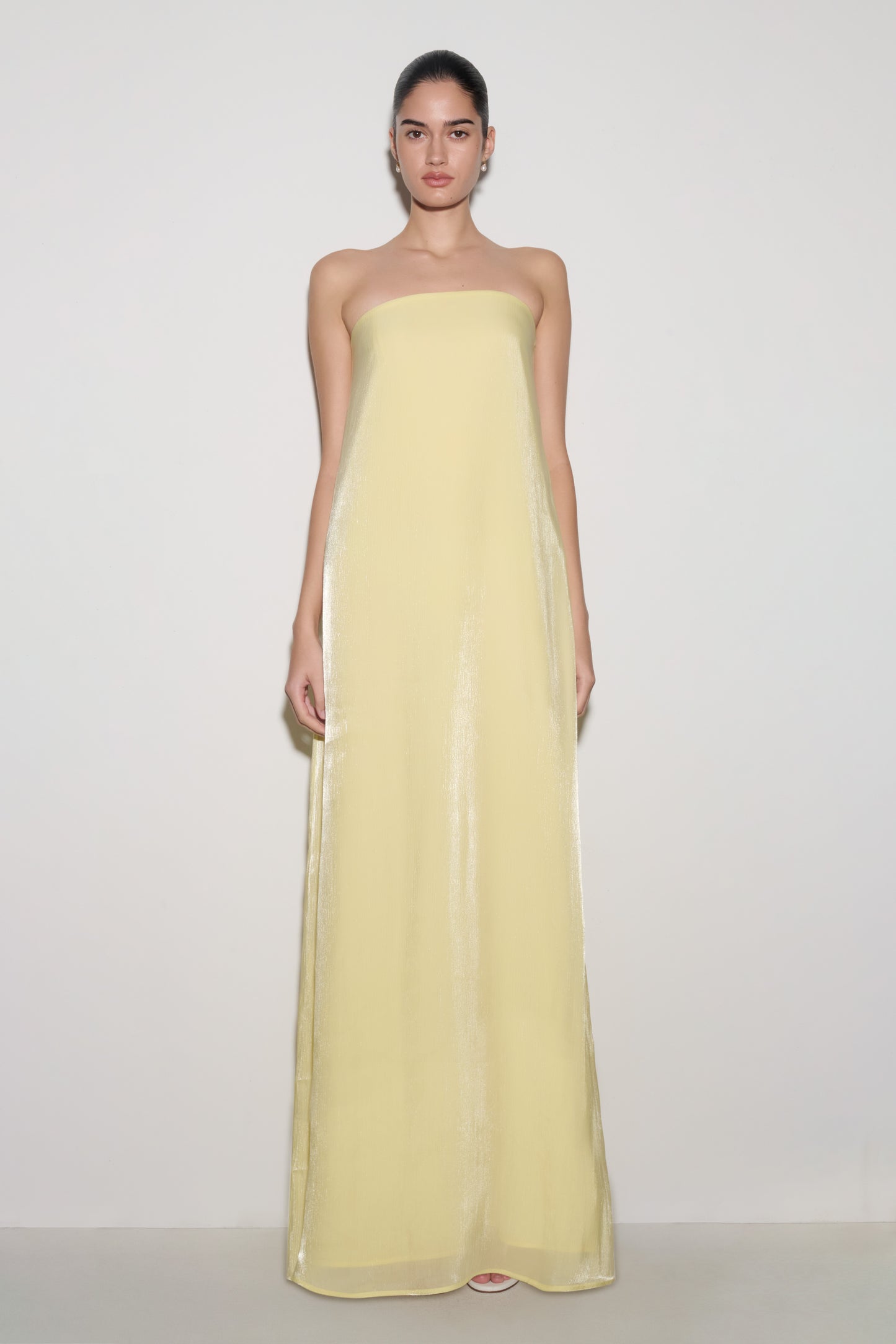 Woman wearing light yellow strapless maxi dress.