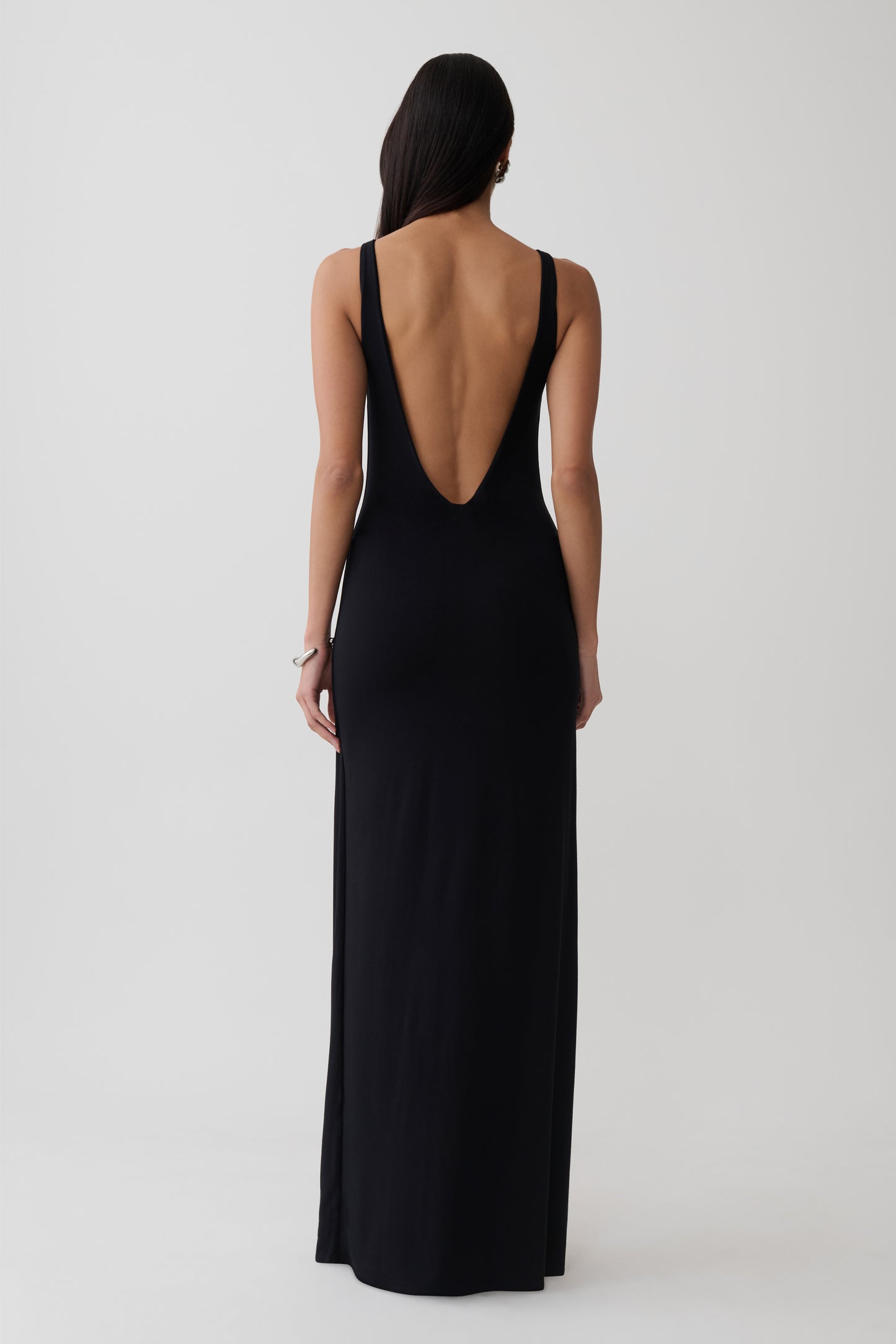 Woman wearing a black backless twist maxi dress.