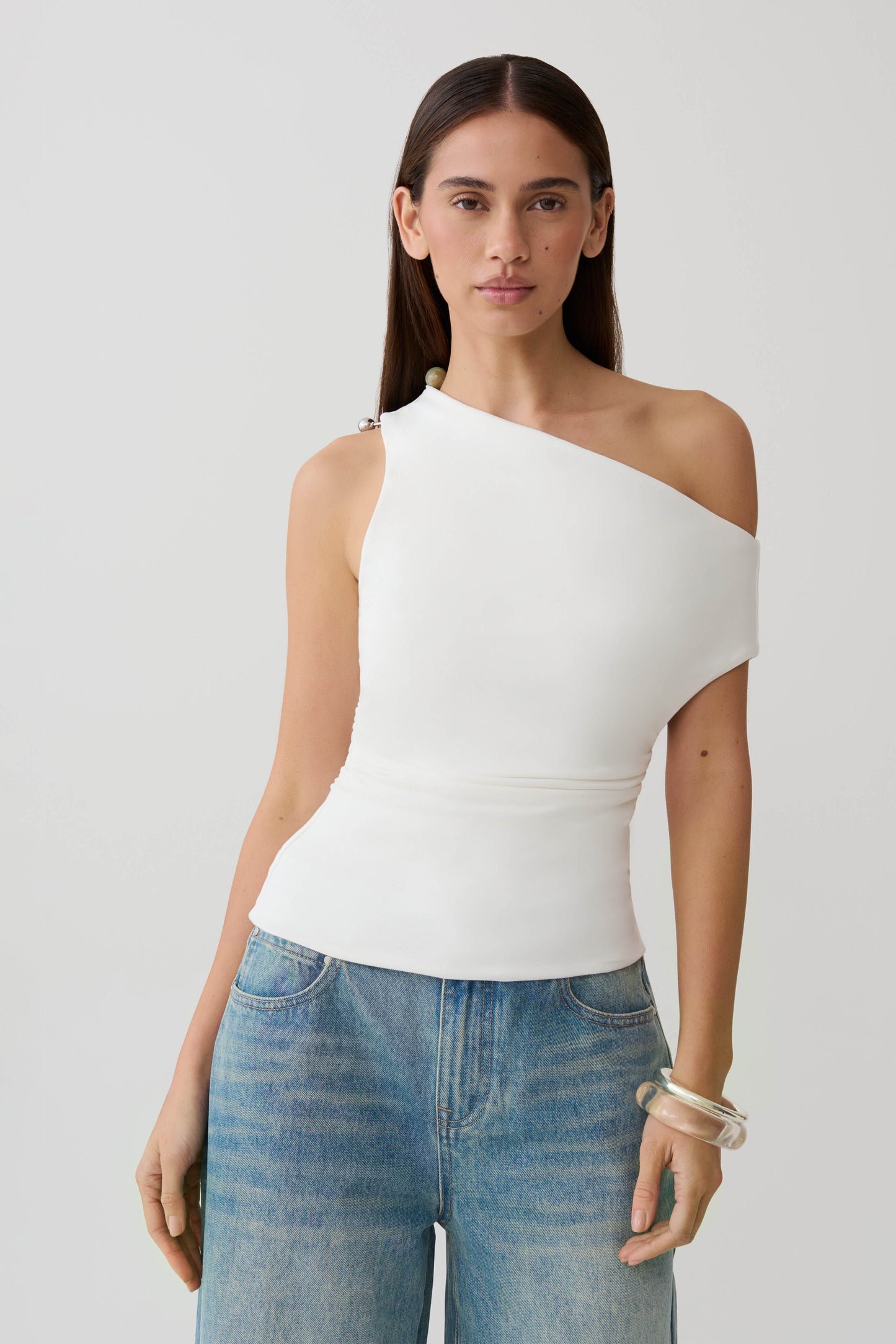 Woman wearing a white short sleeve draped hardware top.