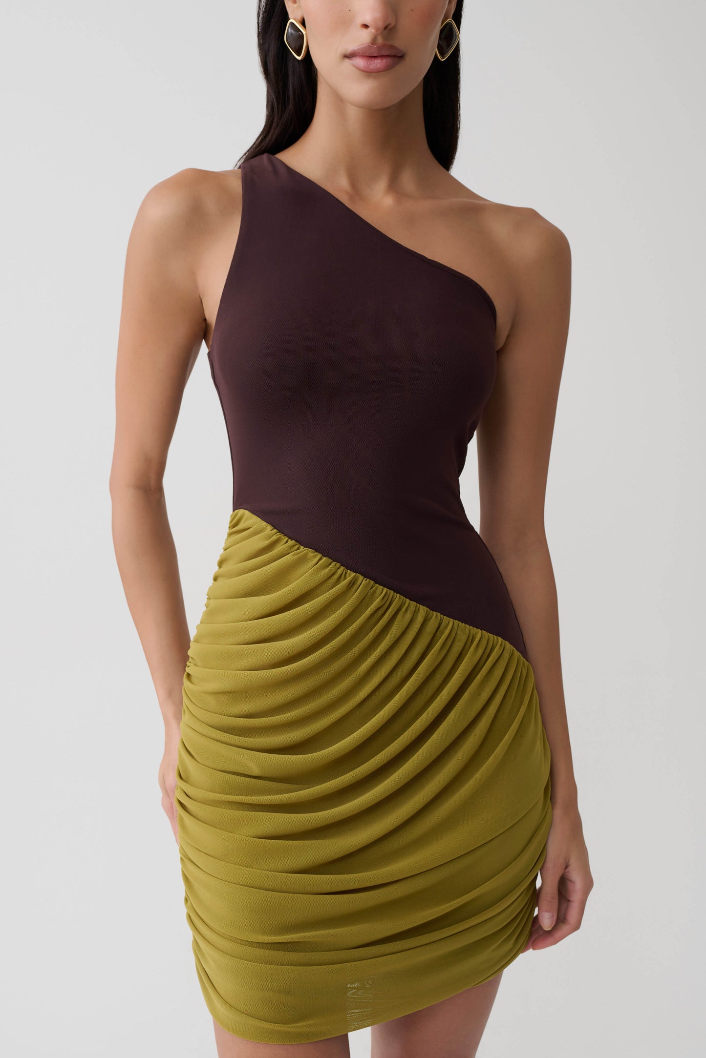 Woman wearing a green and brown asymmetric two toned mini dress.