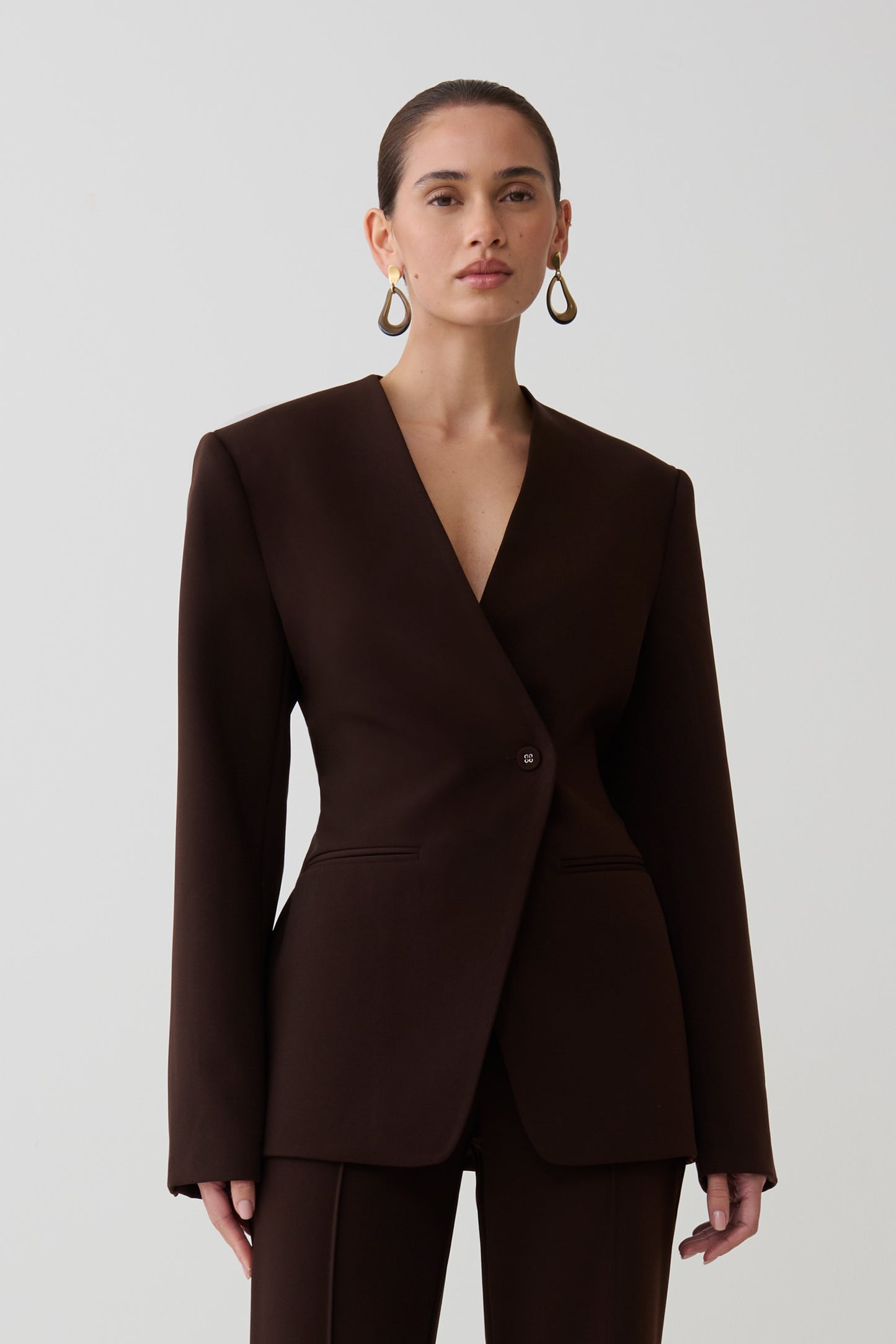 Woman wearing dark brown drop shoulder suiting blazer.