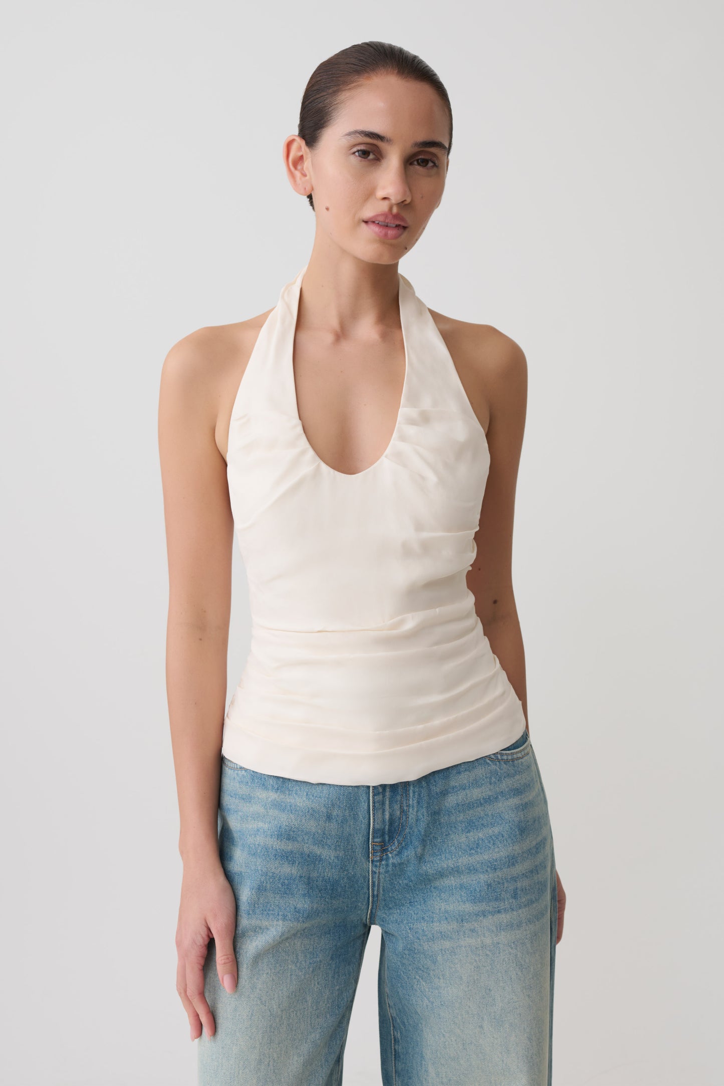 Woman wearing a white ruched halter top.