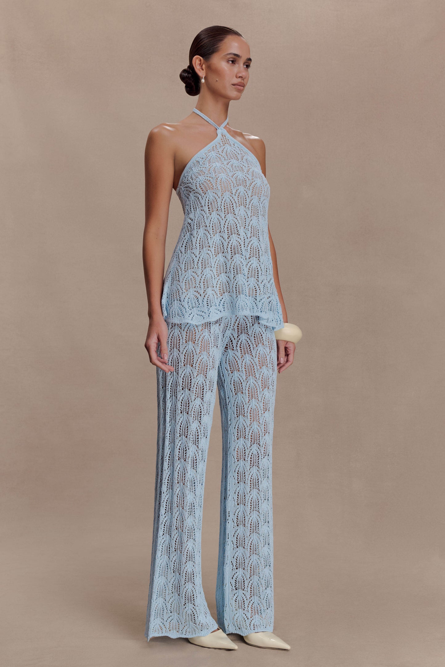 Woman wearing a light blue crochet halter top.