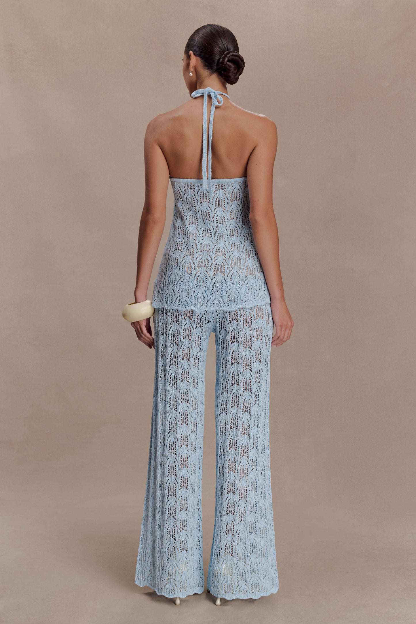 Woman wearing a light blue crochet halter top.