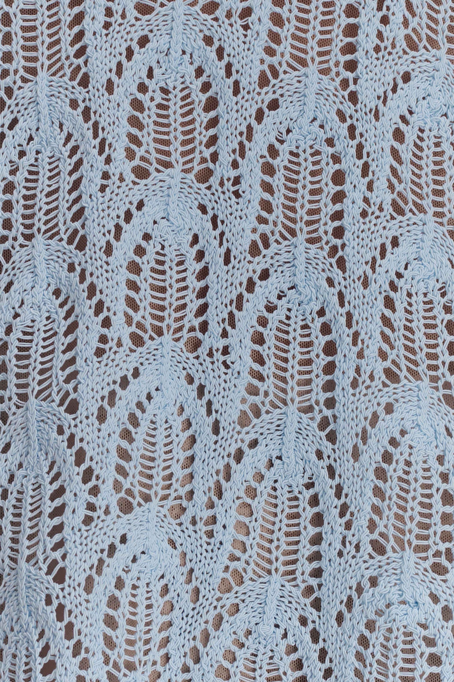 Close-up of a textured light blue crochet fabric.