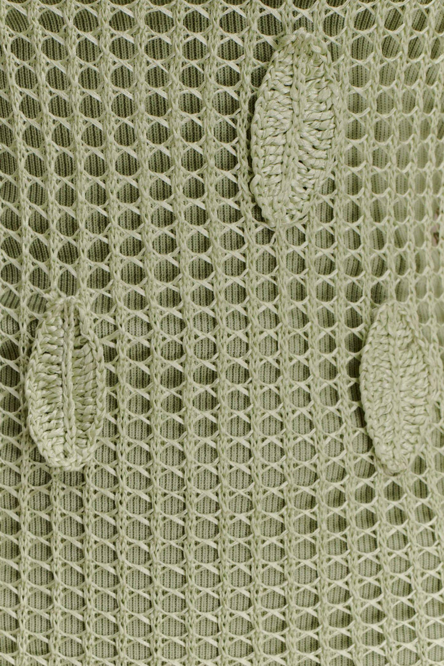 Close-up of a textured green crochet fabric with leaf detailing.