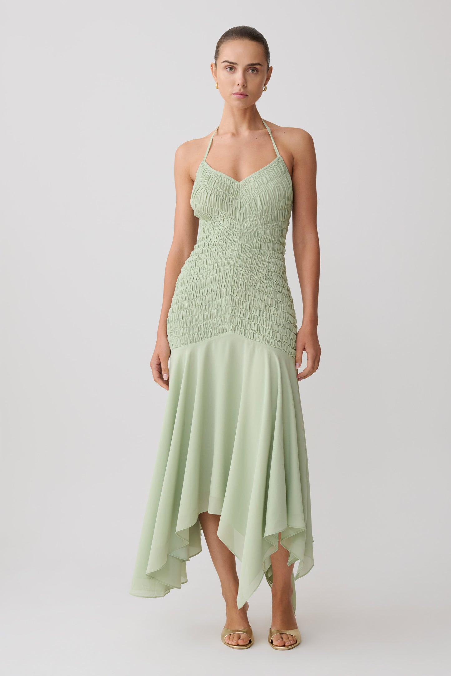 Woman wearing a light green shirred chiffon maxi dress.