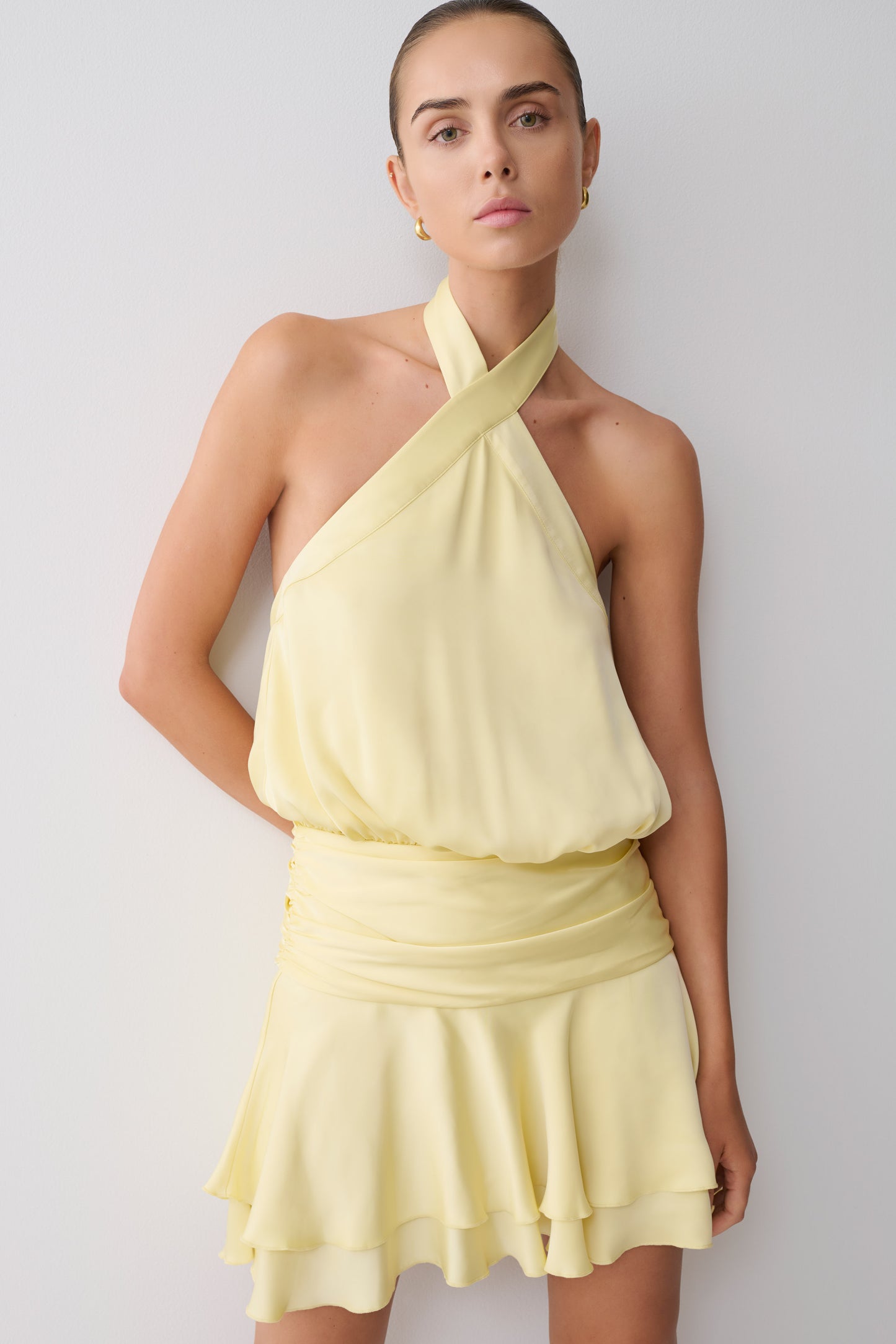 Woman wearing a light yellow halter neck mini dress.
