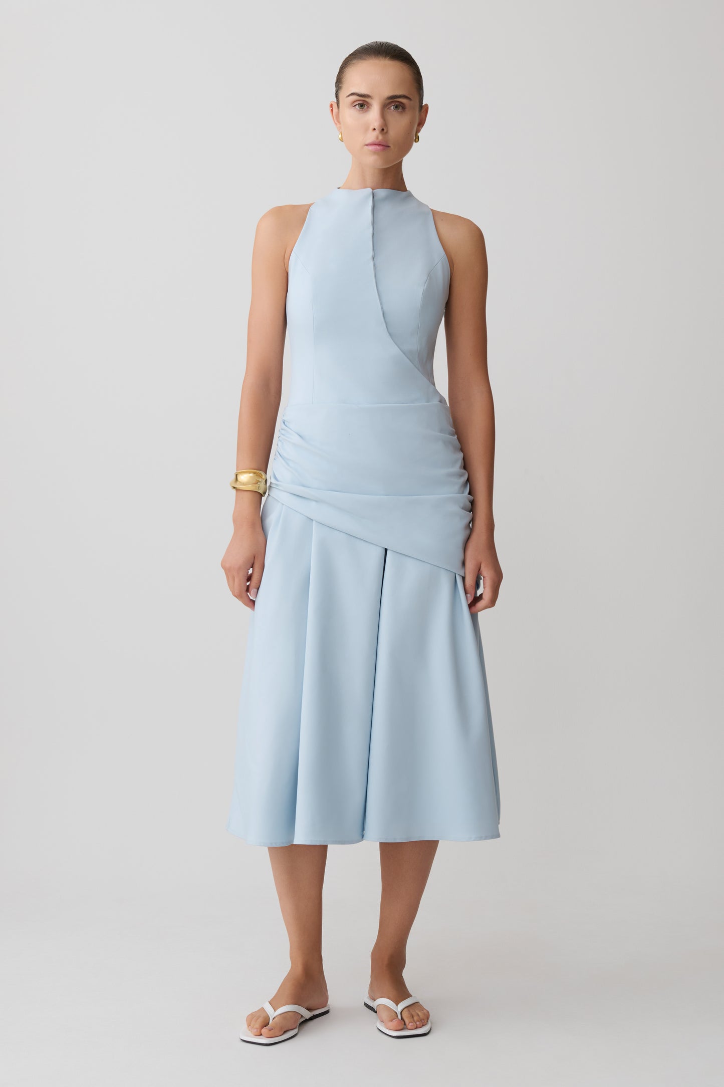 Woman wearing a light blue wrapped waist midi dress.