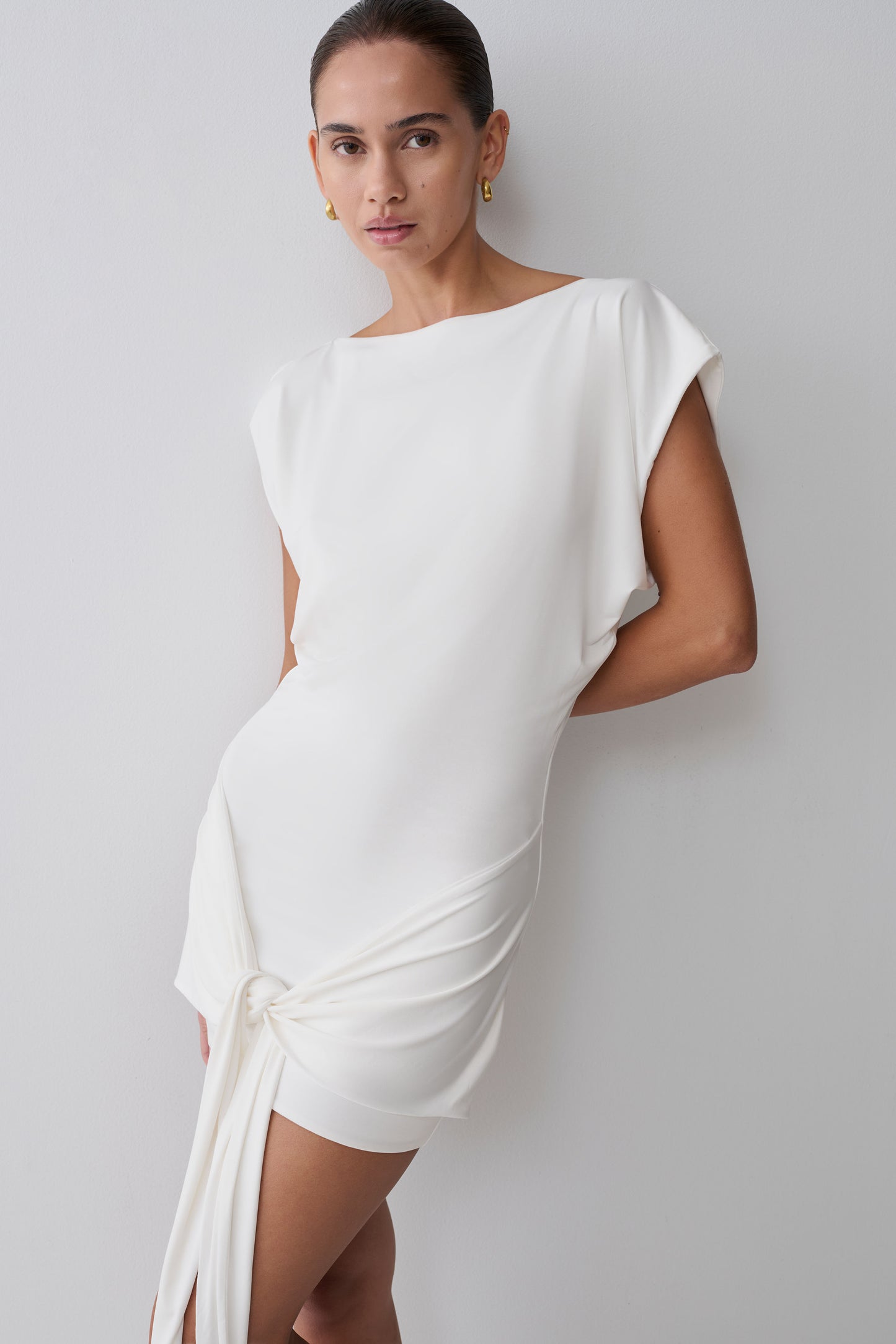 Woman wearing a white dress with waist tie.