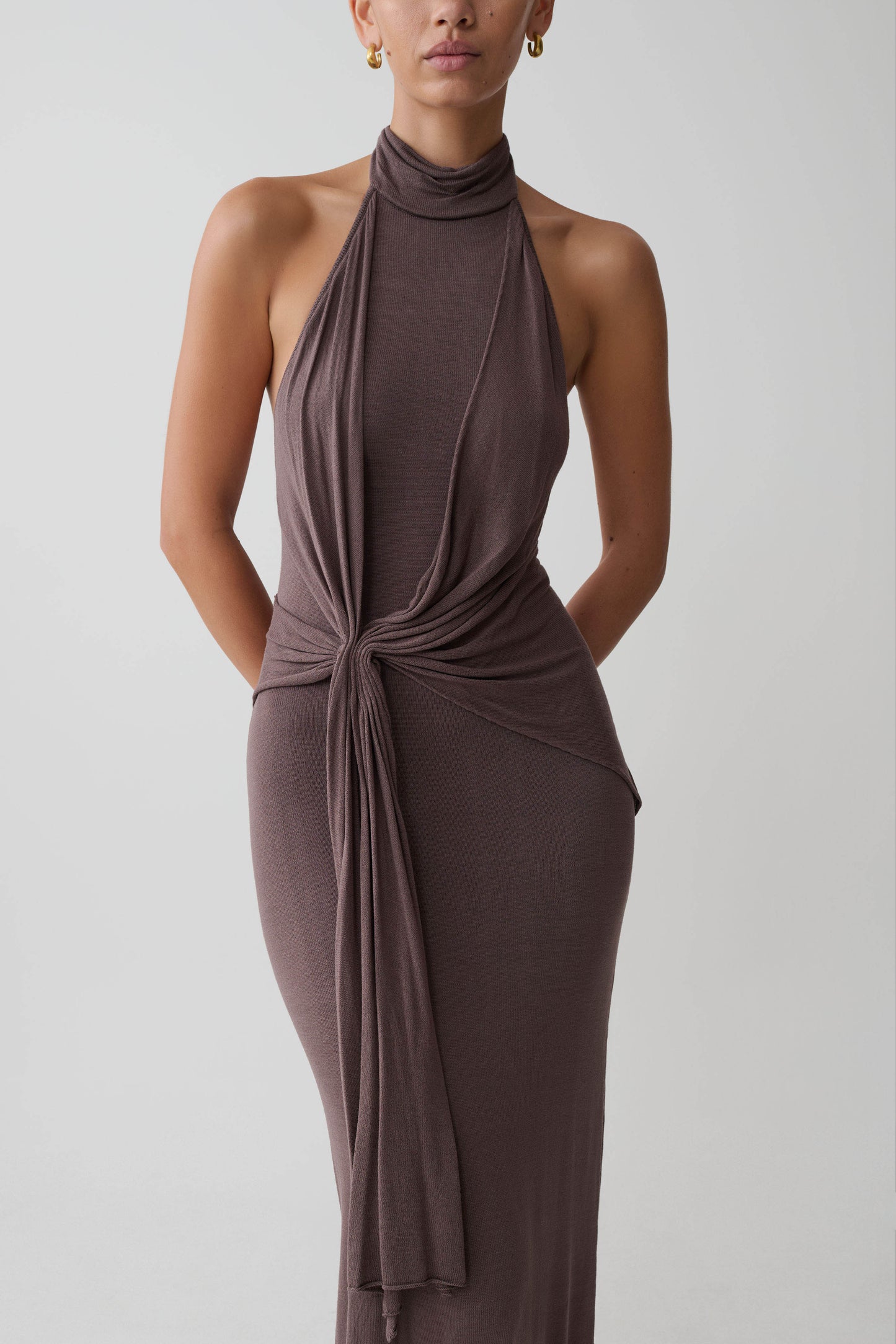 Woman wearing a brown halter neck dress.