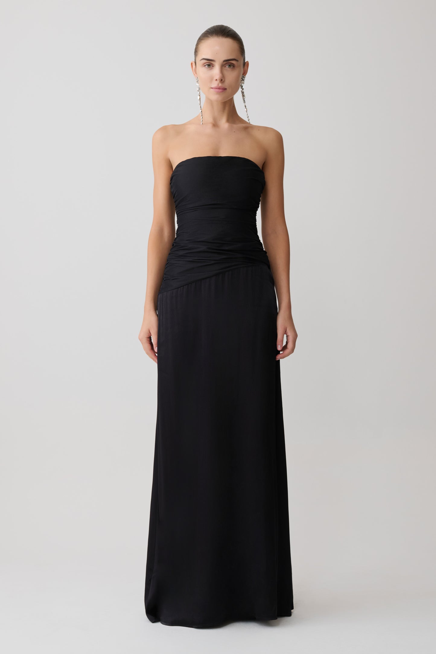 Woman wearing a black strapless gown on a white background