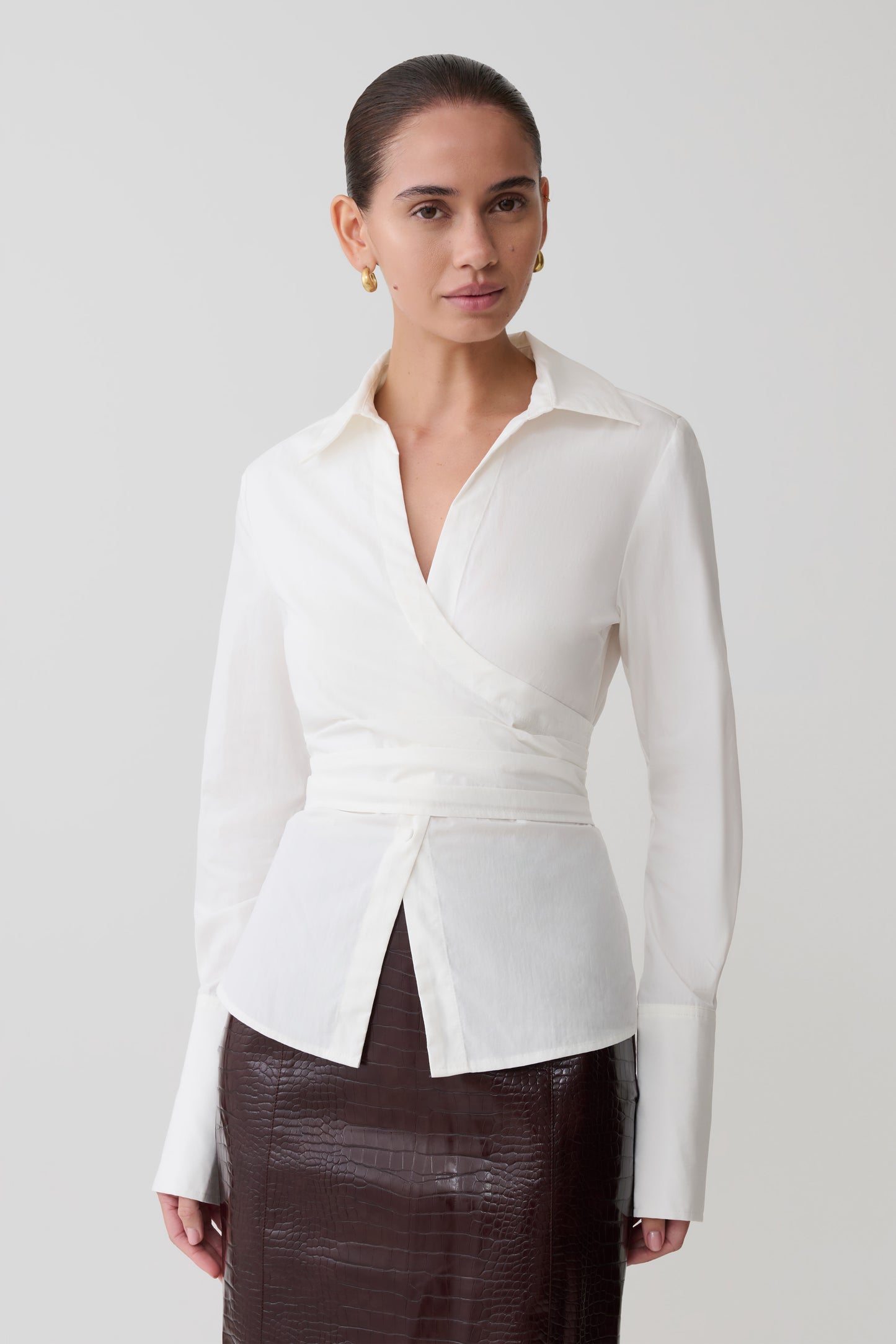 Woman wearing a white blouse with a V-neckline on a plain background