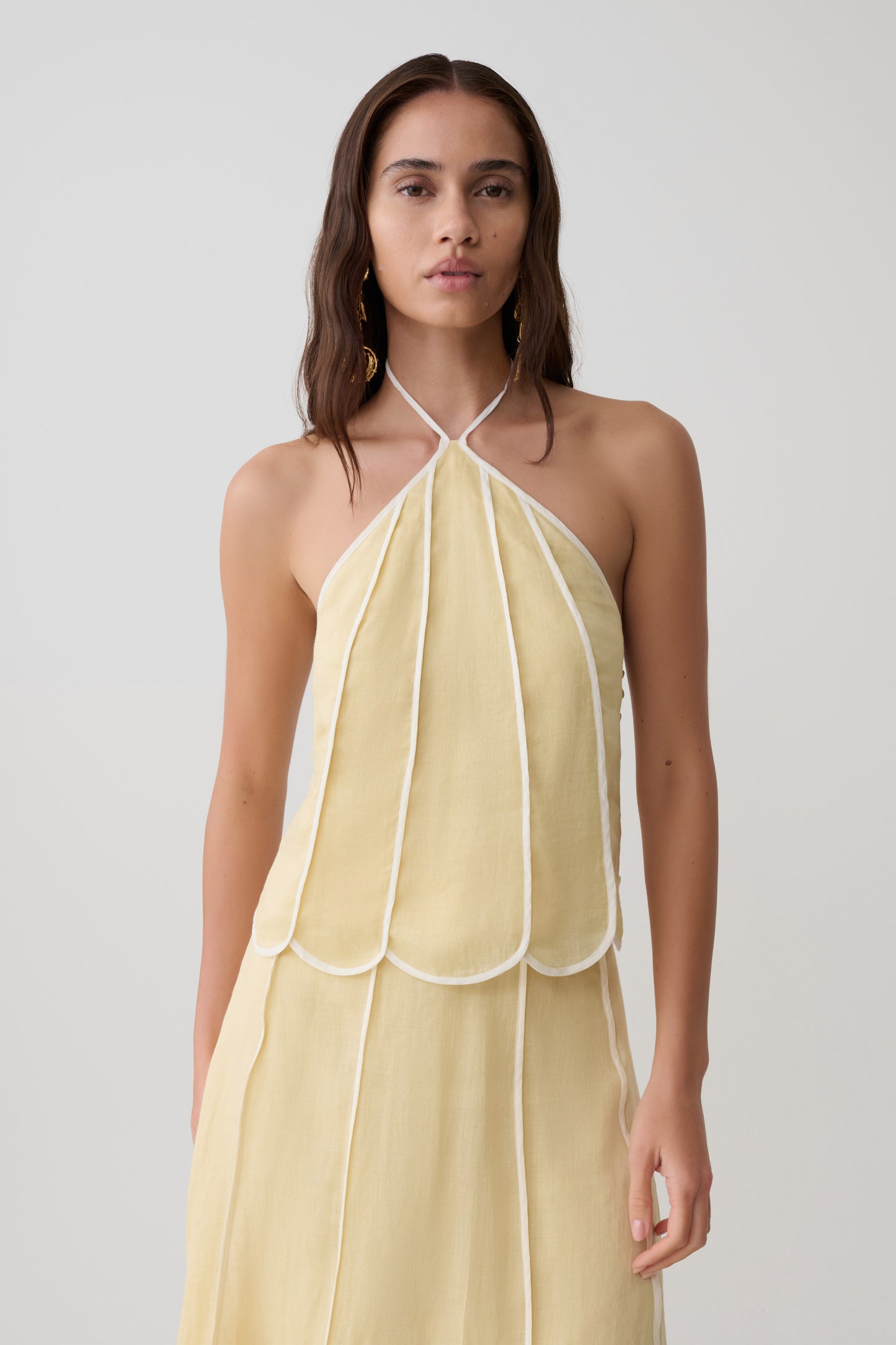 Woman wearing a light yellow panelled halter sleeveless top.