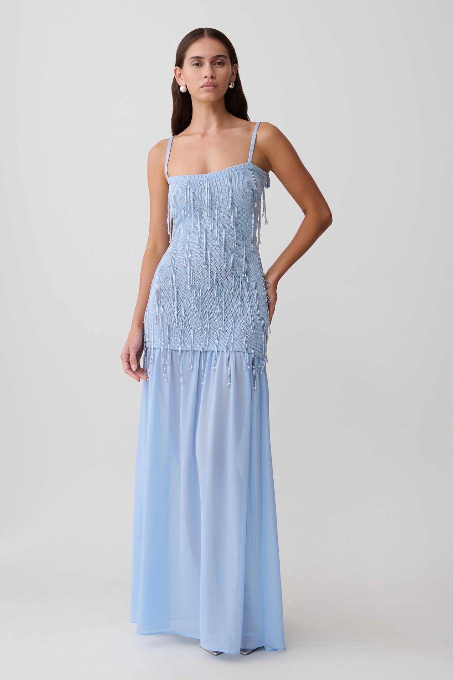 Woman wearing a light blue beaded knit and chiffon maxi dress.