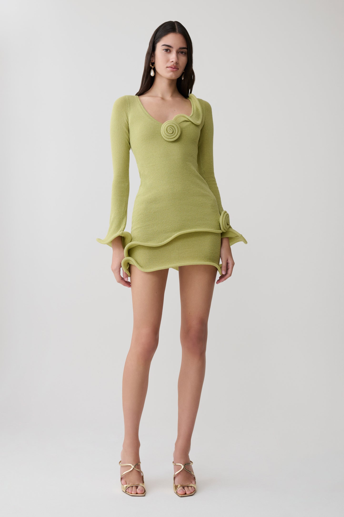 Woman wearing a light green knit long sleeve mini dress.
