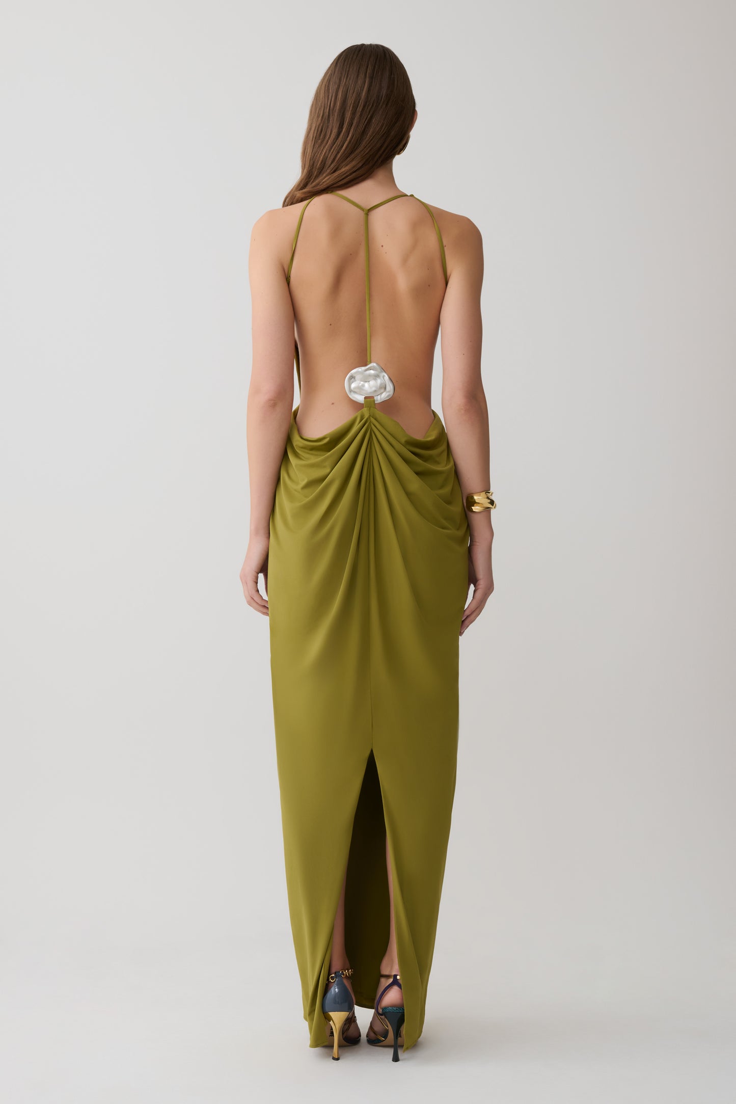 Woman wearing a green low back halter maxi dress.