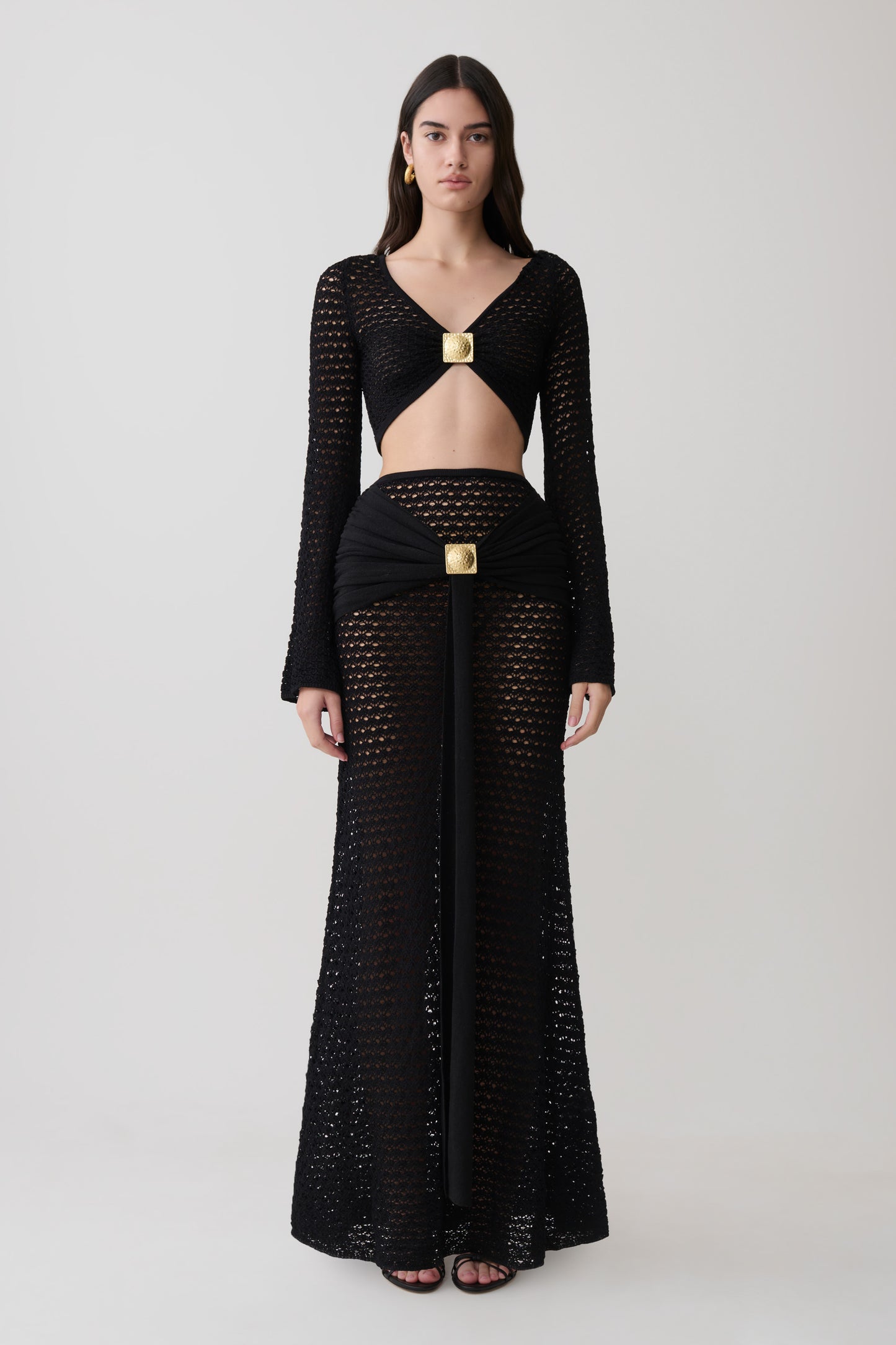 Woman wearing crochet long sleeve cropped top with matching maxi skirt.