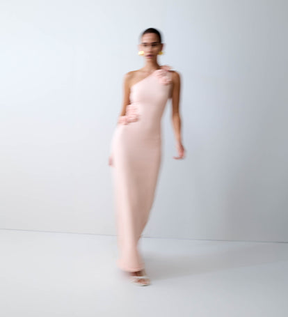 Woman wearing a one shoulder pink maxi dress.