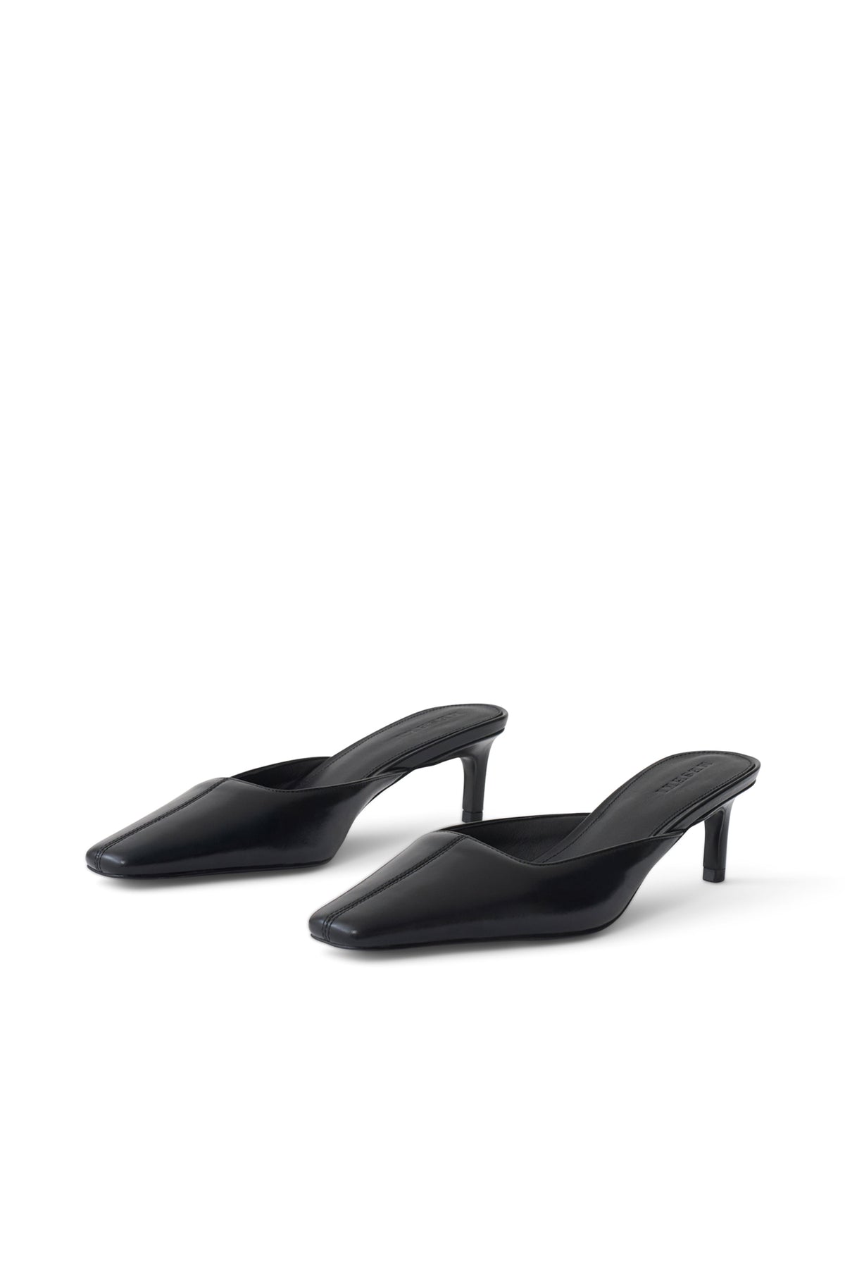 A pair of black pointed-toe mule heels with slim kitten heels, shown from a three-quarters angle on a clean white background.