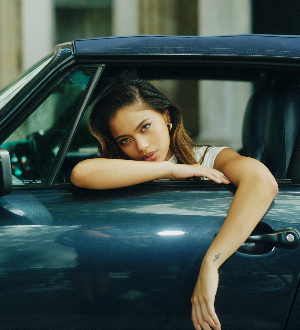 Woman leaning out of a car window, looking at the camera.