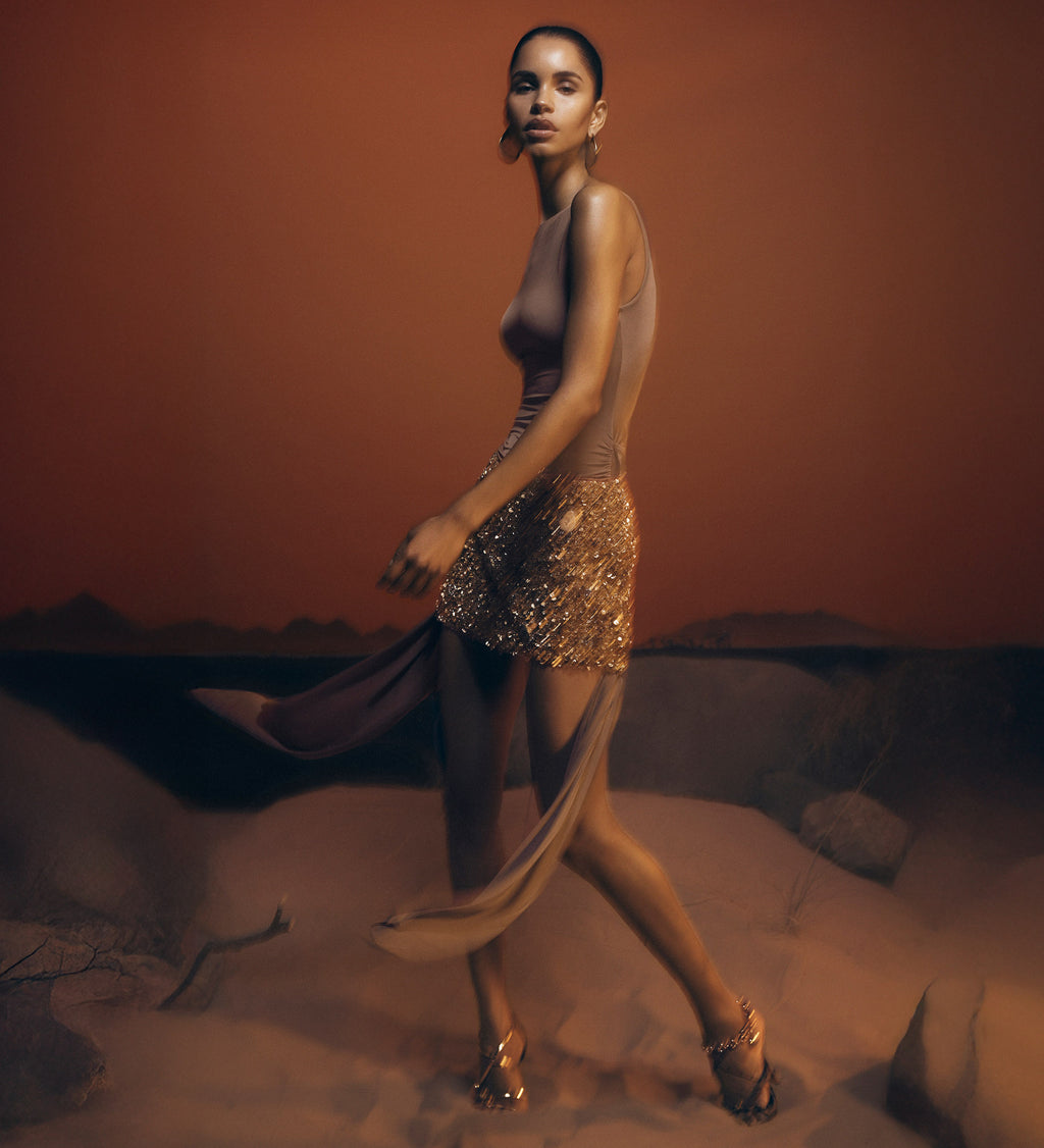 Woman in a flowing dress with a desert landscape in the background.