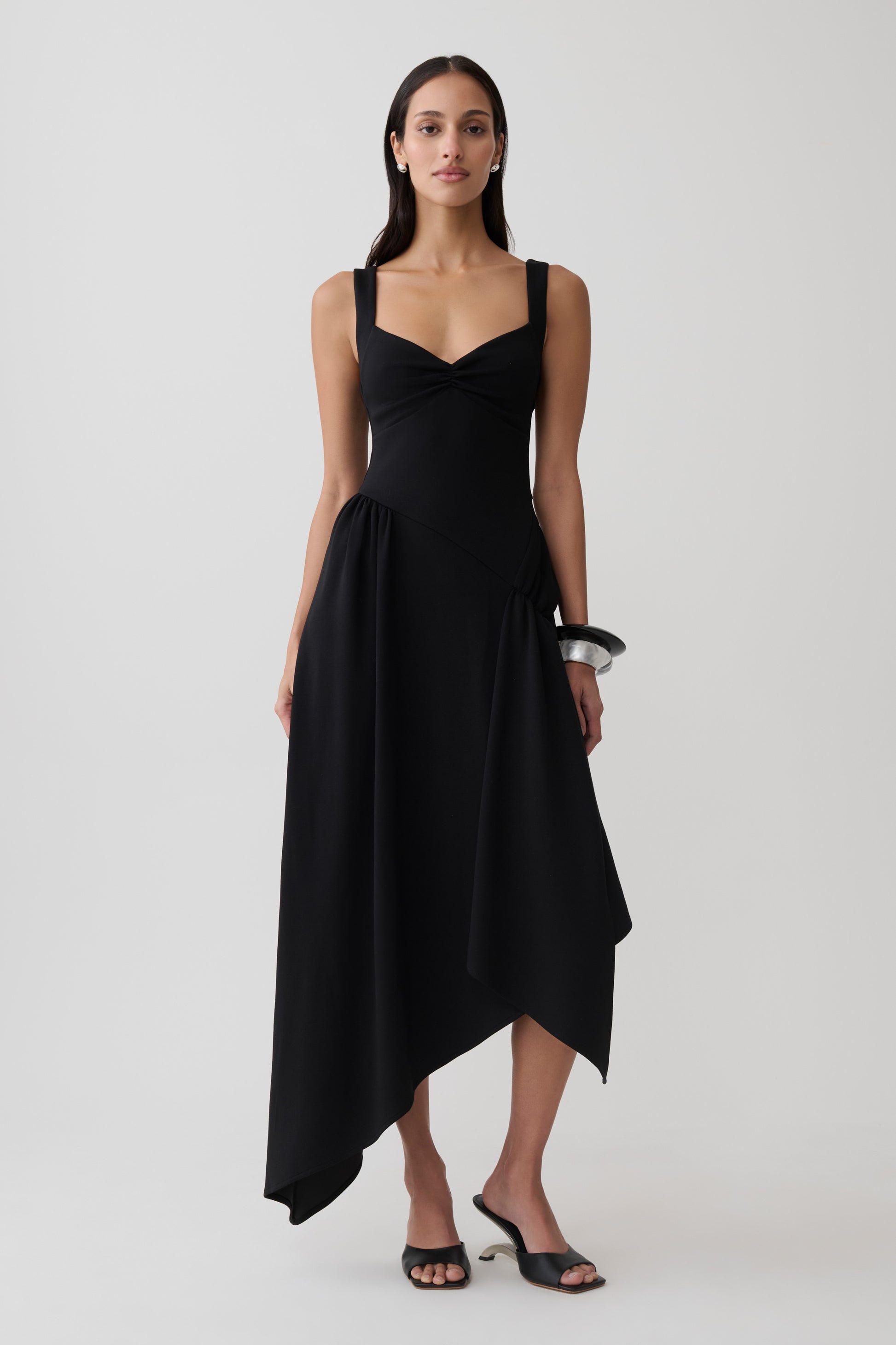 Woman wearing a black asymmetric hem midi dress.