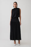Woman wearing a black sleeveless drop waist gathered midaxi dress.