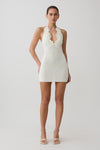 Woman wearing a white crochet halter mini dress.
