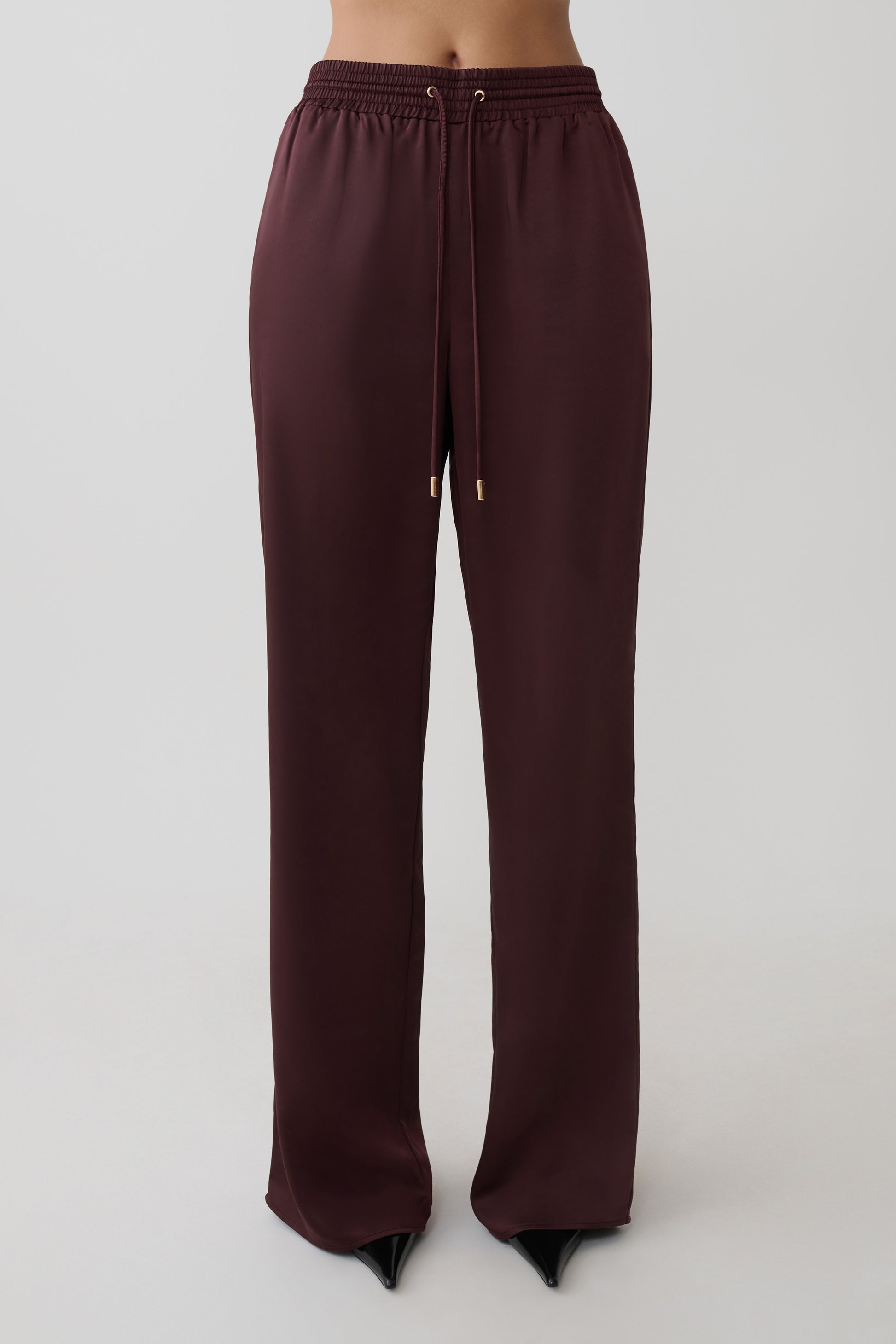 Woman wearing brown straight leg satin pants.