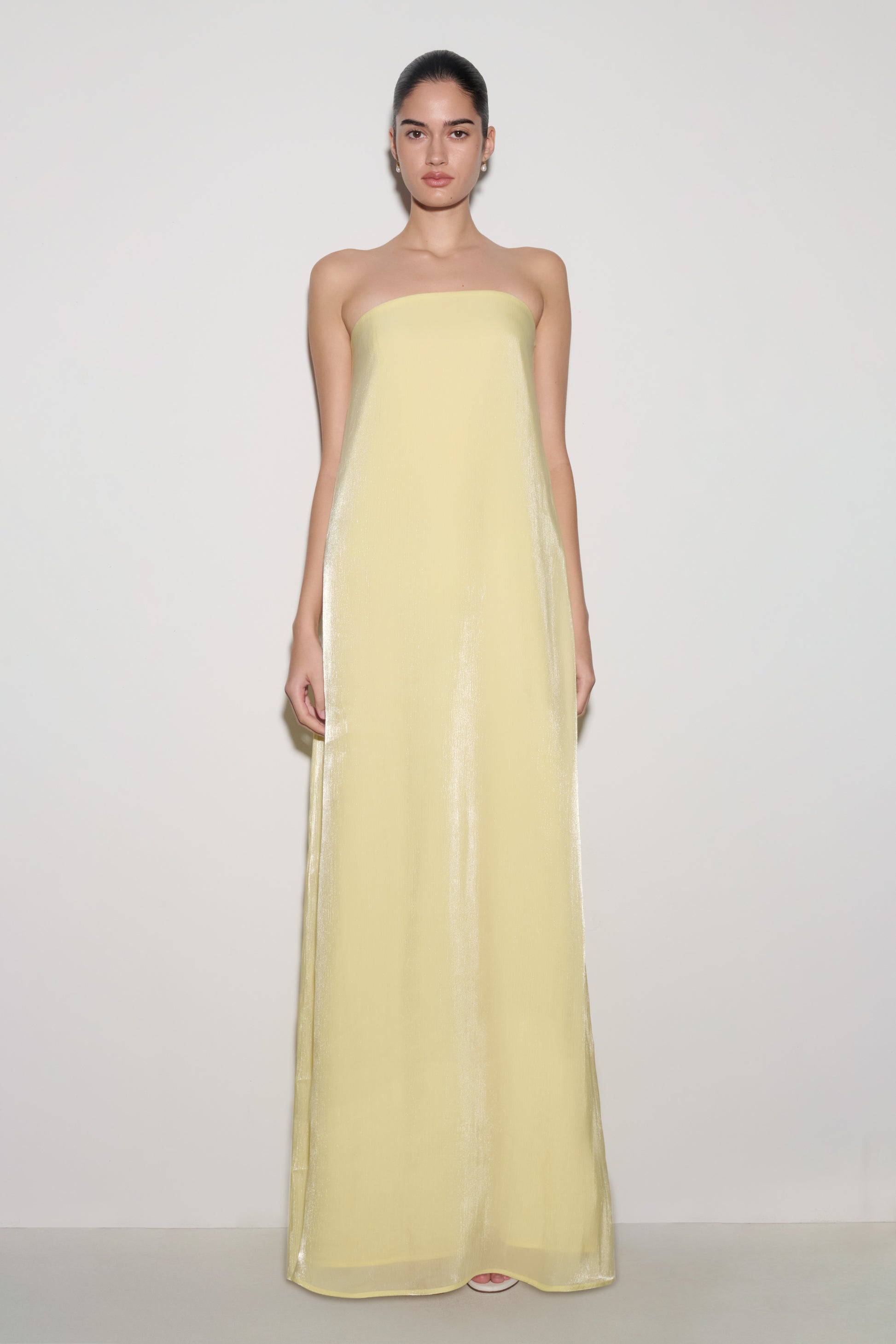 Woman wearing light yellow strapless maxi dress.