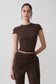 Woman wearing a brown high neck top with piping detail.