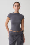 Woman wearing a grey high neck top with piping detail.