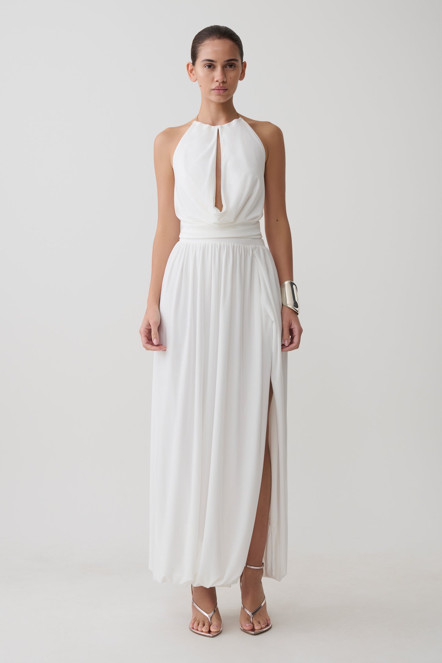 Woman wearing a white halter neck top with hardware witthe matching midi skirt.