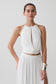 Woman wearing a white halter neck top with hardware.