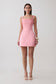 Woman wearing a pink satin corset mini dress.