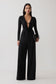 Woman wearing black cowl long sleeve slinky bodysuit, with black pants.