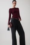Woman wearing a burgundy long sleeve sheer top.