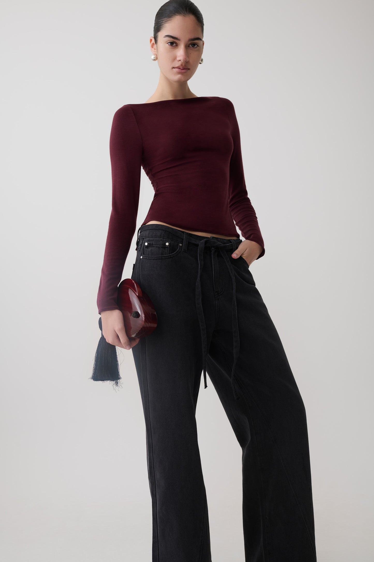 Woman wearing a burgundy long sleeve sheer top.