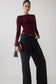 Woman wearing a burgundy long sleeve sheer top.