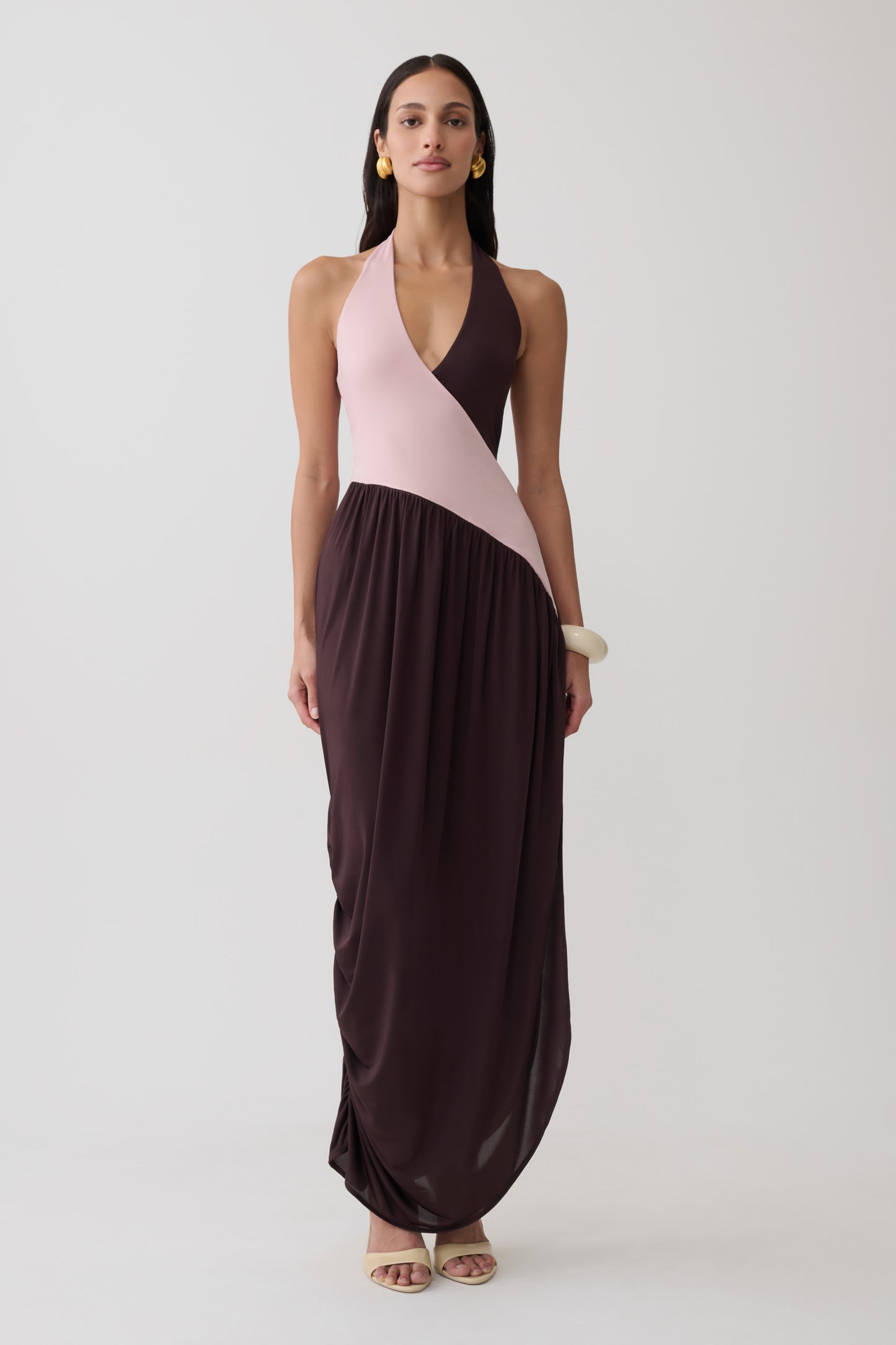Woman wearing a pink and brown halter gathered maxi dress.