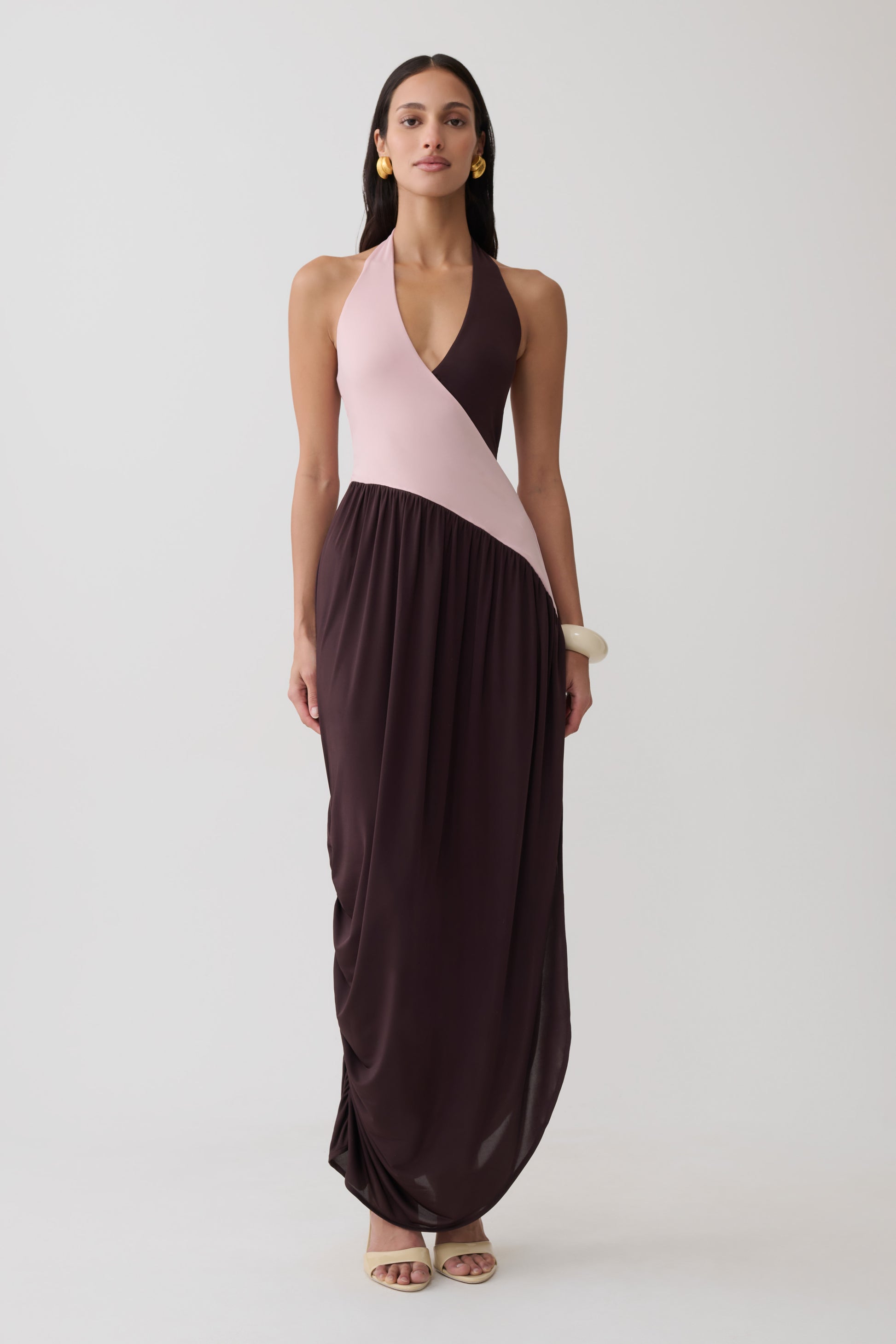 Woman wearing a pink and brown halter gathered maxi dress.