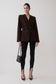 Woman wearing a brown blazer and knit black leggings.