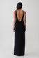 Woman wearing a black backless twist maxi dress.