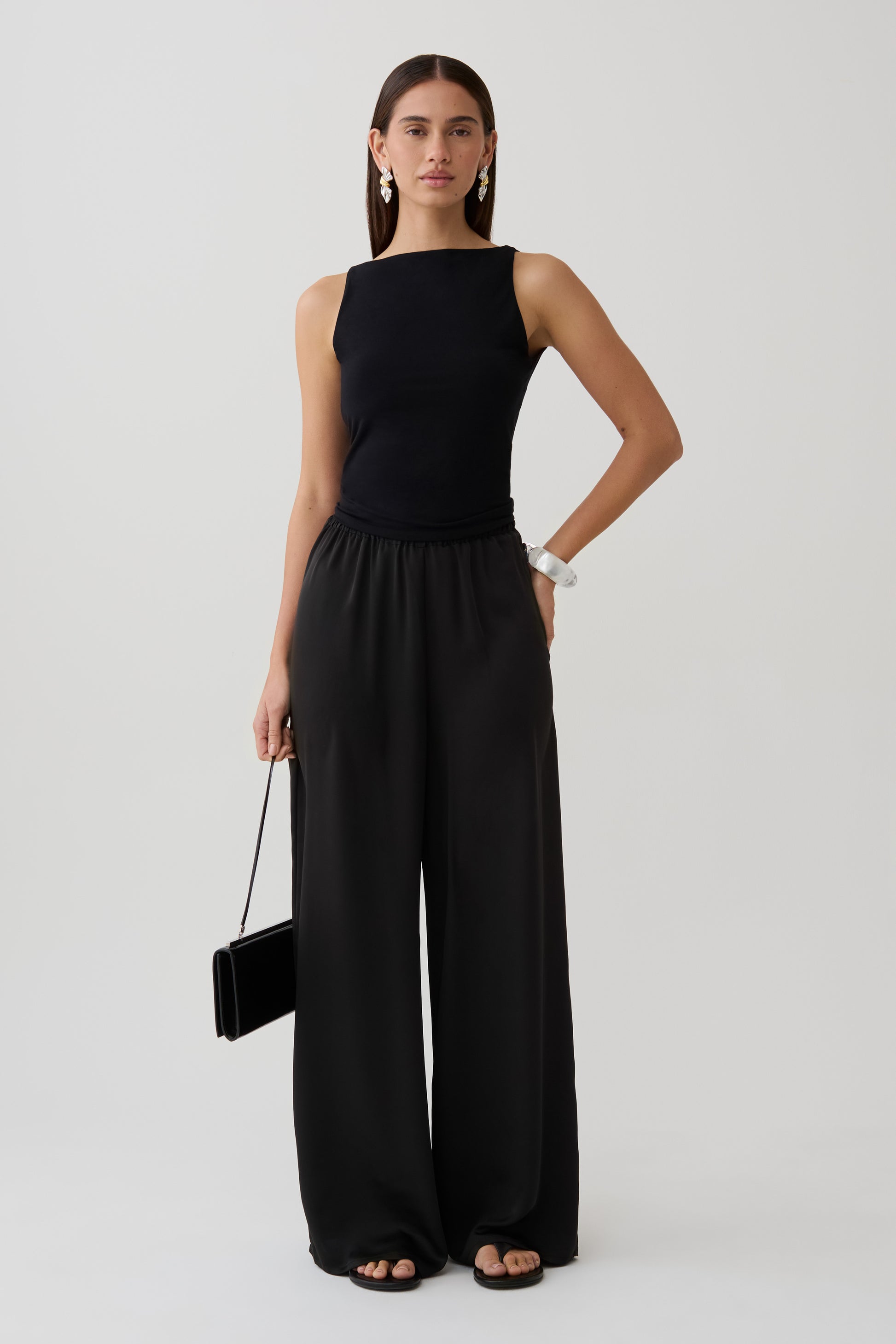 Woman wearing a black sleeveless top with satin and lace straight pants.