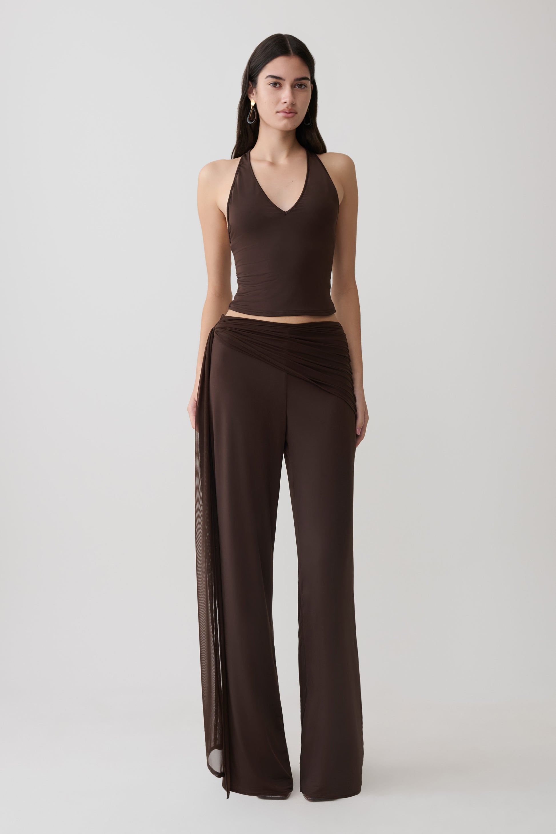 Woman wearing a brown slinky and mesh top with slinky gathered wide leg pants.