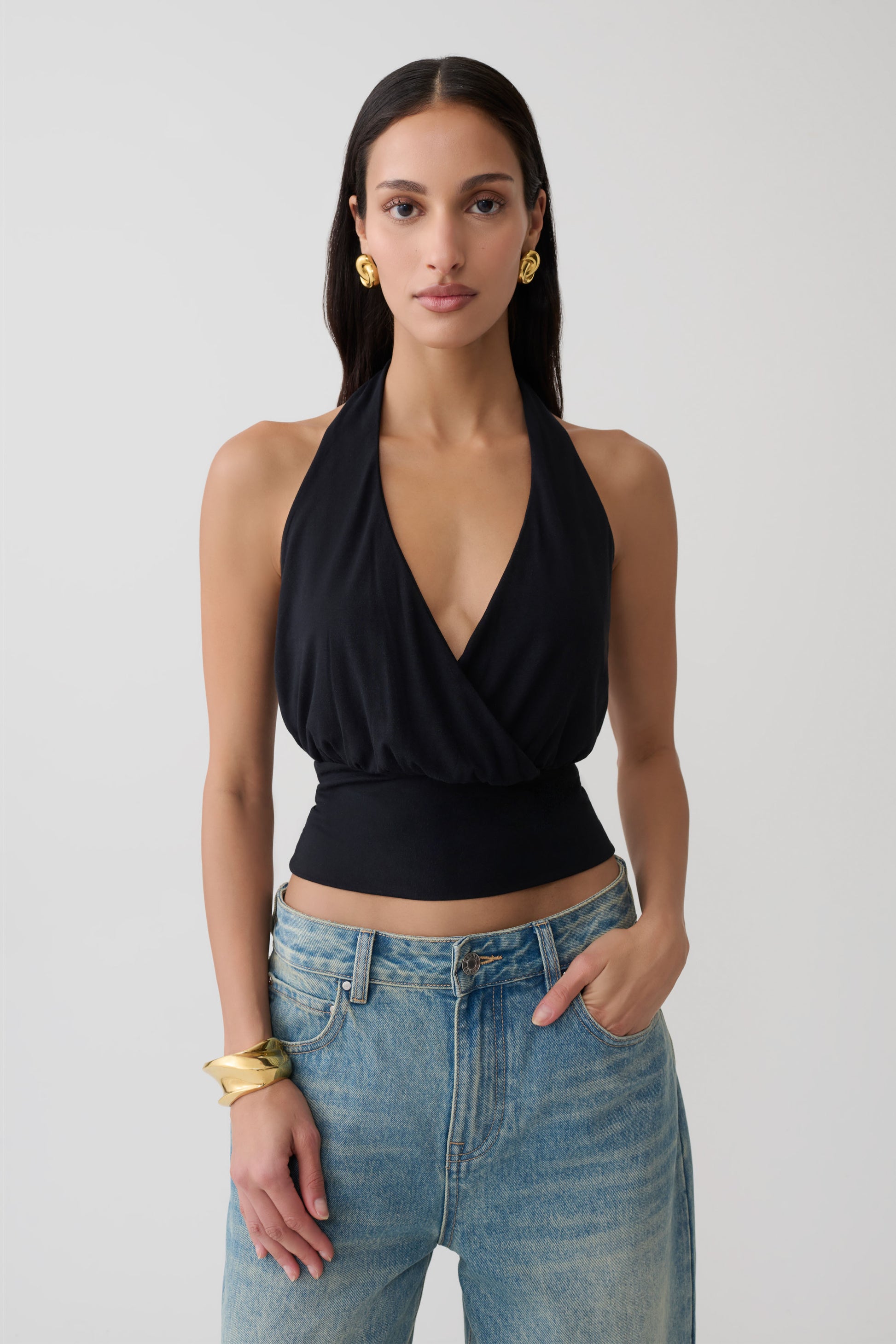 Woman wearing a black draped halter top. 