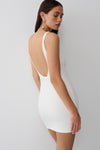Woman wearing a white backless twist mini dress.