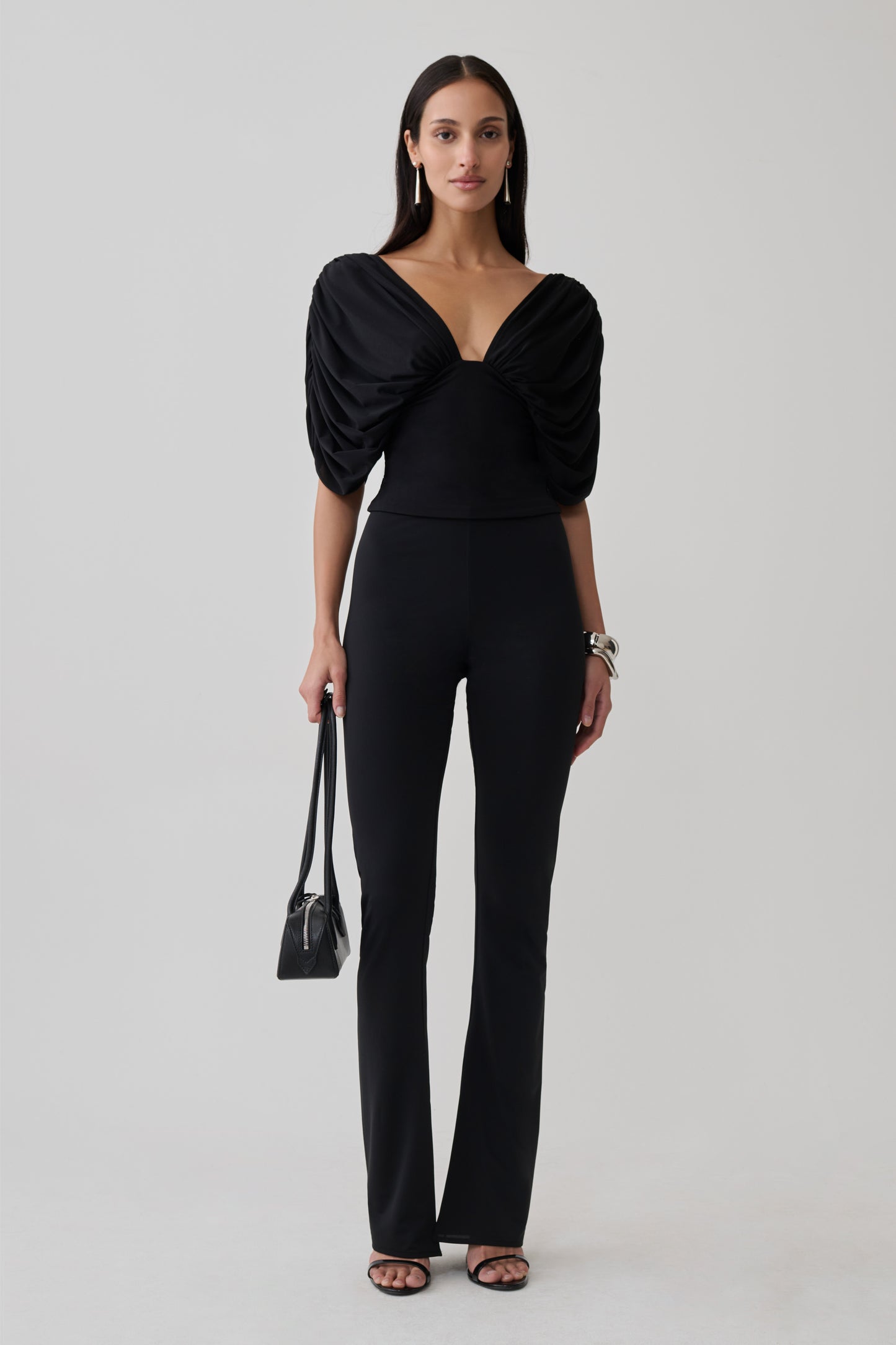 Woman wearing a gathered bodice top with skinny flare pants.