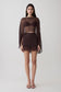 Woman wearing brown bralette with chiffon cape with matching lace and satin mini skirt.